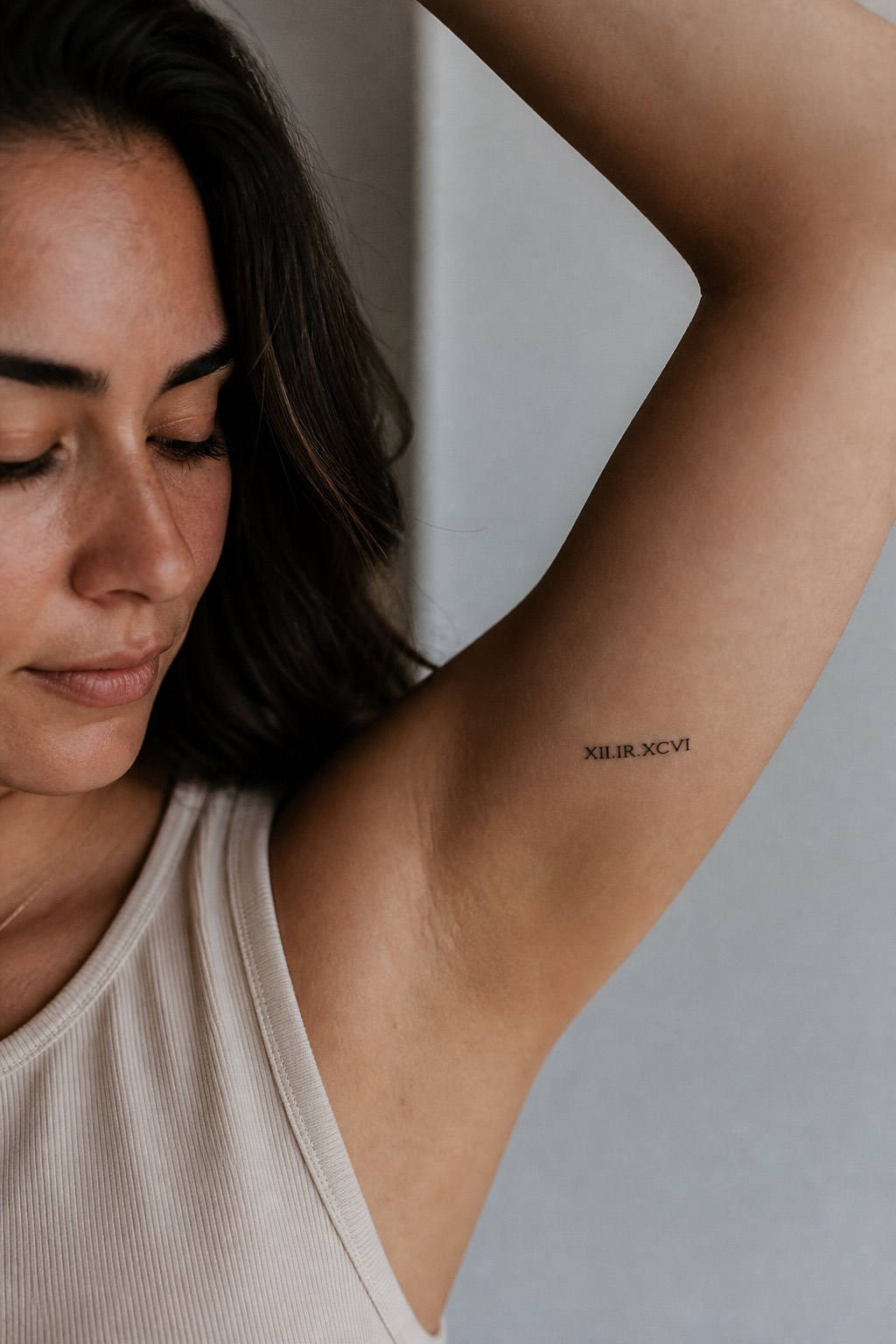 Micro Roman numeral inner bicep tattoo for women