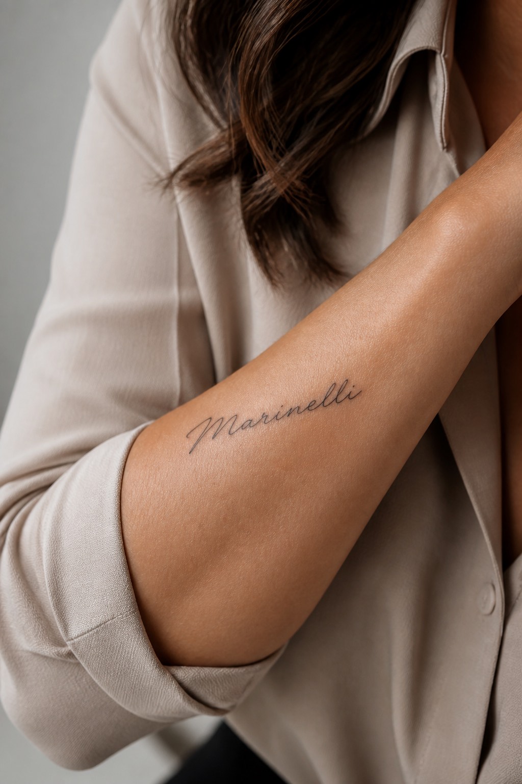 Elegant script family name accent tattoo for women